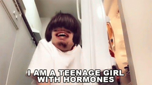 A Man In A White Shirt Says " I Am A Teenage Girl With Hormones " While Looking Into A Refrigerator GIF