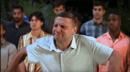A Man In A White Shirt Stands In Front Of A Crowd Of Men GIF