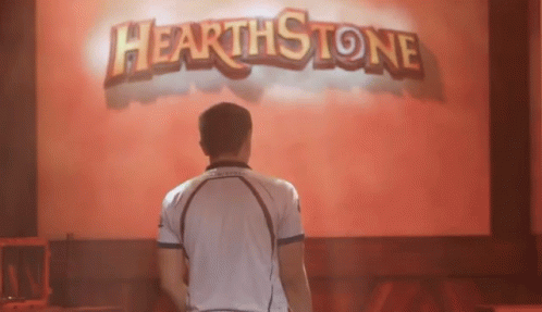 A Man In A White Shirt Stands In Front Of A Hearthstone Sign GIF