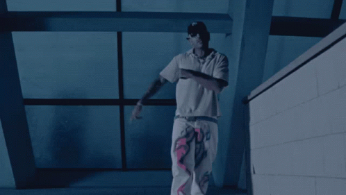 A Man In A White Shirt Stands In Front Of A Window GIF