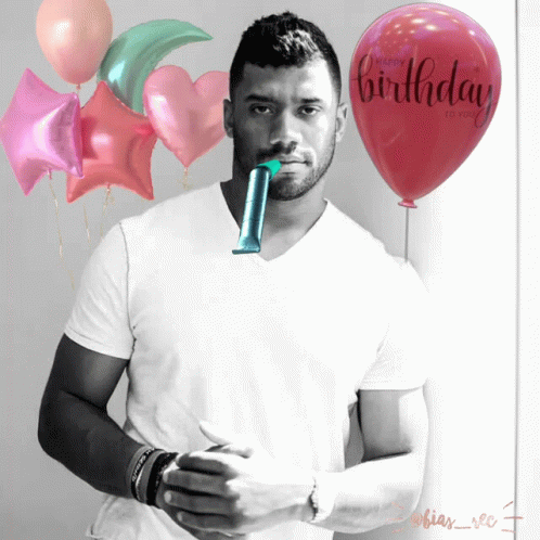 A Man In A White Shirt Stands In Front Of Balloons That Say Happy Birthday To You GIF