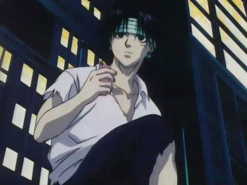 A Man In A White Shirt With A Bandana On His Head Is Sitting In Front Of A Building GIF