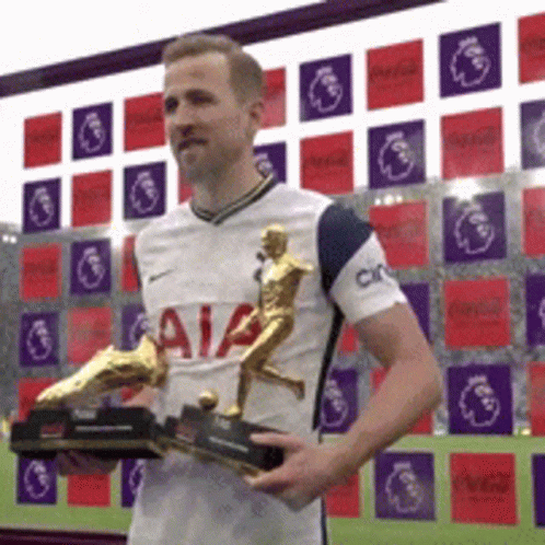 A Man In A White Shirt With Aia On It Is Holding Two Trophies GIF