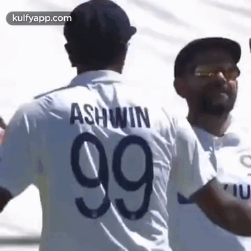 A Man In A White Shirt With The Number 99 On It Is Standing Next To Another Man In A Black Hat . GIF