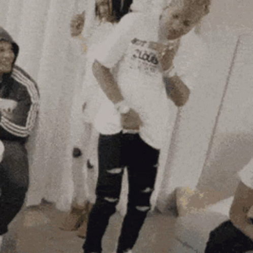 A Man In A White Shirt With The Word Clouds On It Is Standing In A Room With Other People . GIF