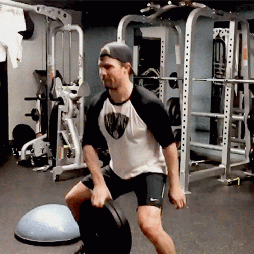 A Man In A White Shirt With The Word Mustang On It Is Squatting GIF