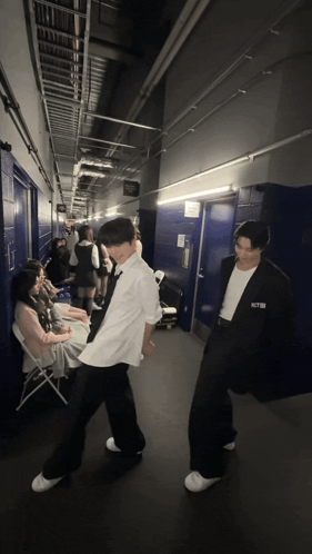 A Man In A White Shirt With The Word Nct On It Stands In A Hallway GIF