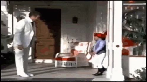 A Man In A White Suit And Tie Is Standing Next To A Little Girl On A Porch . GIF