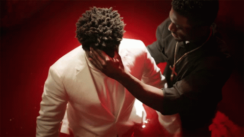 A Man In A White Suit Is Being Touched By Another Man In A Black Shirt GIF