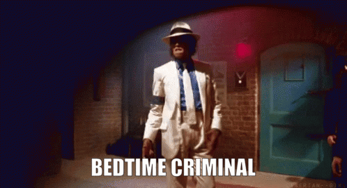 A Man In A White Suit Is Dancing In A Dark Room With The Words Bedtime Criminal Below Him GIF