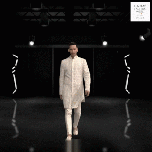A Man In A White Suit Is Standing In Front Of A Lakme Fashion Week Sign GIF
