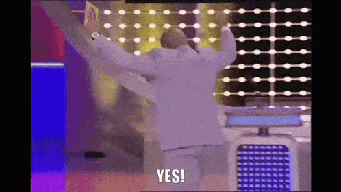 A Man In A White Suit Is Standing In Front Of A Wall With His Arms Outstretched And Says Yes . GIF