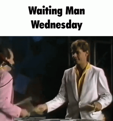 A Man In A White Suit Shakes Hands With A Woman In A Pink Shirt While Waiting For Wednesday . GIF