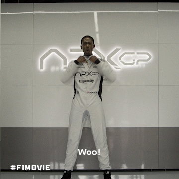 A Man In A White Suit Stands In Front Of A Sign That Says Nxgp GIF
