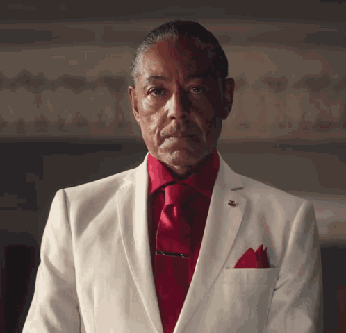 A Man In A White Suit With A Red Tie GIF