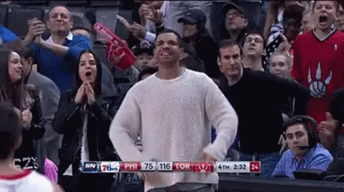 A Man In A White Sweater Is Dancing In Front Of A Crowd Of People . GIF