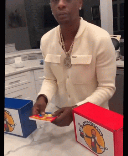 A Man In A White Sweater Is Opening A Box That Has The Word Magic On It GIF