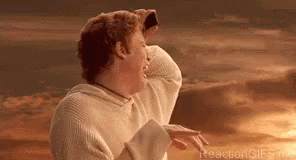 A Man In A White Sweater Is Standing In Front Of A Sunset With His Hands On His Head . GIF