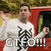 A Man In A White Sweater Is Standing Next To A Red Truck And Making A Funny Face . GIF