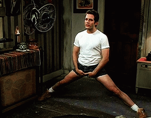 A Man In A White T-Shirt And Shorts Is Stretching His Legs . GIF