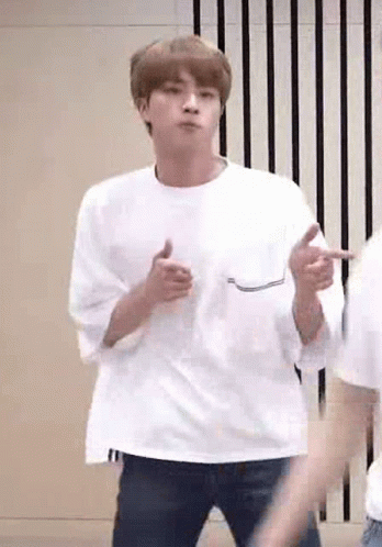 A Man In A White T-Shirt Is Dancing In A Room . GIF