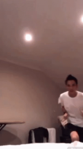 A Man In A White T-Shirt Is Jumping In The Air GIF