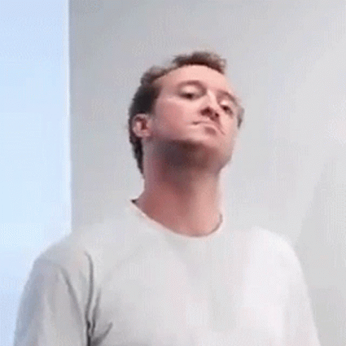 a man in a white t-shirt is looking up at something .