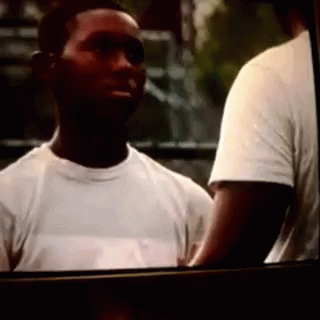 A Man In A White T-Shirt Is Standing Next To Another Man GIF