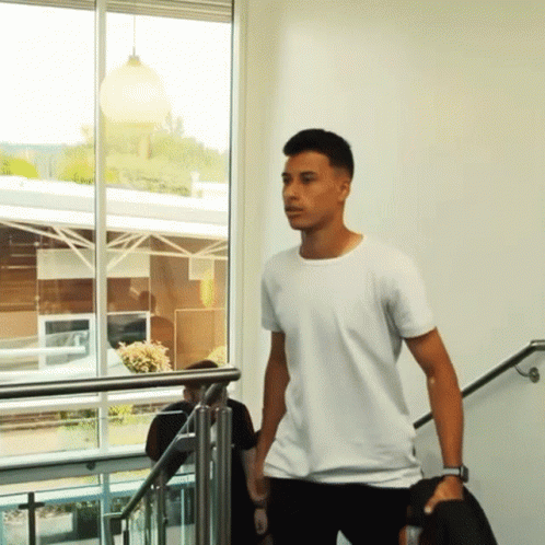 a man in a white t-shirt is walking down stairs