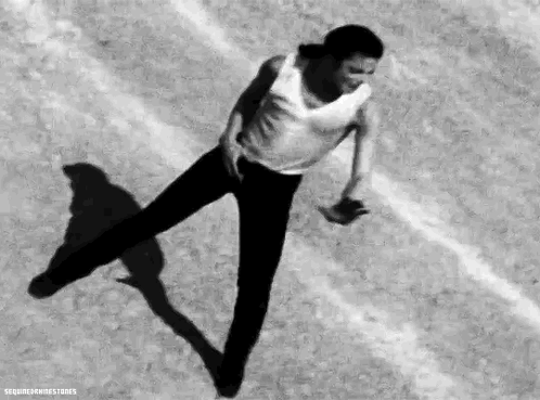 a man in a white tank top and black pants is dancing on a track .