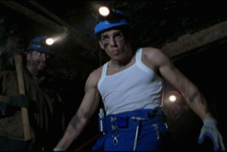 A Man In A White Tank Top And Blue Pants Has A Belt With Tools On It GIF