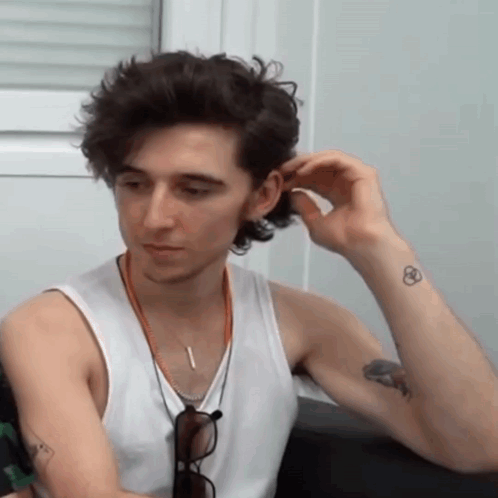 A Man In A White Tank Top Has A Tattoo On His Wrist GIF