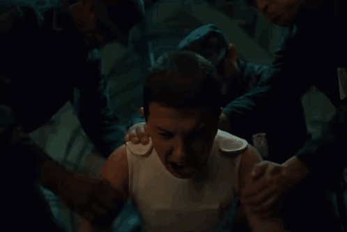 A Man In A White Tank Top Is Being Helped By Two Men . GIF