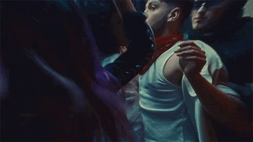 A Man In A White Tank Top Is Holding A Woman In A Crowd Of People GIF
