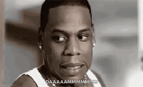 A Man In A White Tank Top Is Making A Funny Face And Saying `` Daaaammmm '' . GIF