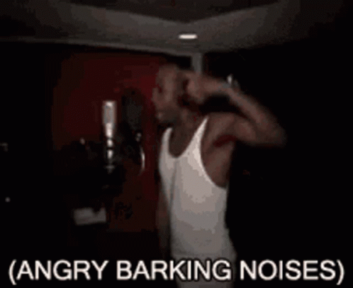 A Man In A White Tank Top Is Singing Into A Microphone With The Words Angry Barking Noises Written Below Him . GIF