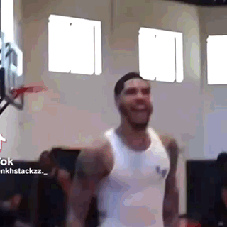 a man in a white tank top is smiling in a gym .