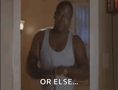 A Man In A White Tank Top Is Standing In A Doorway And Talking To Someone . GIF