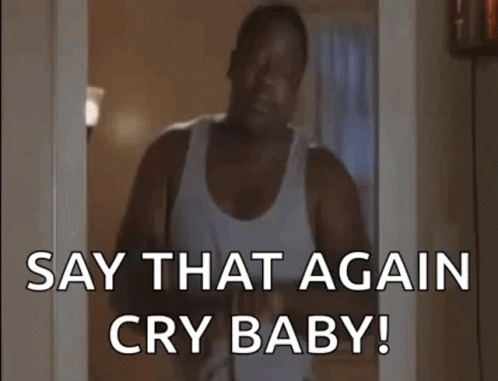 A Man In A White Tank Top Is Standing In A Doorway Holding A Baby And Saying `` Say That Again Cry Baby '' . GIF