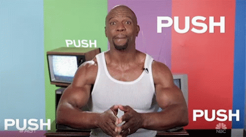 A Man In A White Tank Top Is Standing In Front Of A Colorful Wall That Says Push GIF