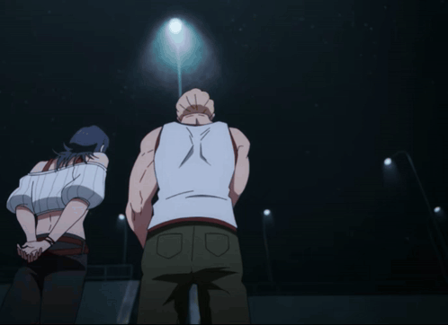 A Man In A White Tank Top Is Standing In Front Of A Woman GIF