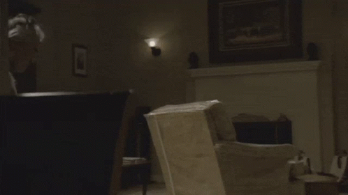 A Man In A White Tank Top Looks At Something GIF