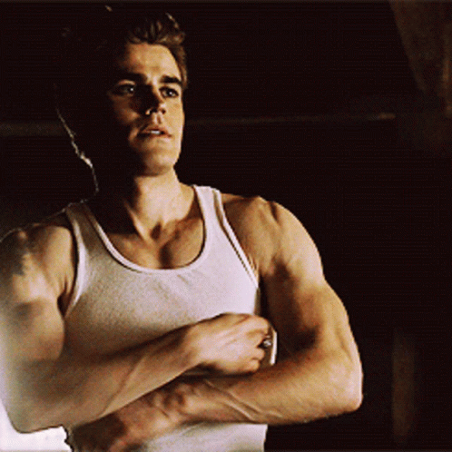 A Man In A White Tank Top Shows Off His Muscles GIF