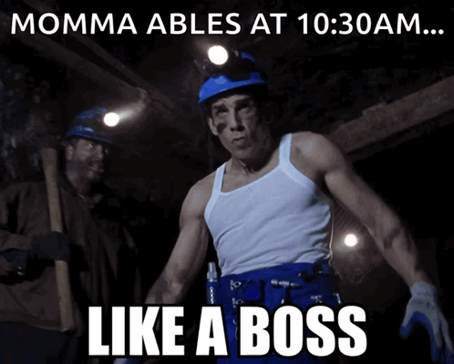 A Man In A White Tank Top Stands In Front Of A Sign That Says " Momma Ables At 10:30 Am ... Like A Boss " GIF