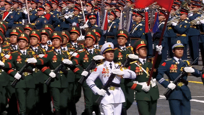 A Man In A White Uniform Stands In Front Of A Large Military March GIF