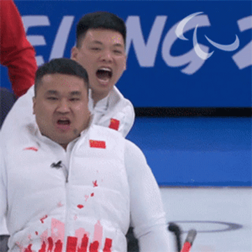 A Man In A White Vest With Chinese Writing On It Is Being Lifted By Another Man GIF