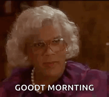 A Man In A Wig And Glasses Is Sitting Down And Saying `` Good Morning '' . GIF