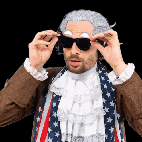 A Man In A Wig And Sunglasses Is Wearing An American Flag GIF