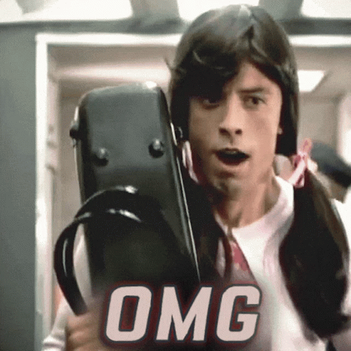 A Man In A Wig Is Holding A Violin Case And The Word Omg Is Behind Him GIF
