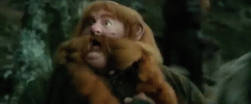 A Man In A Wizard Hat Is Holding A Stick In A Field GIF